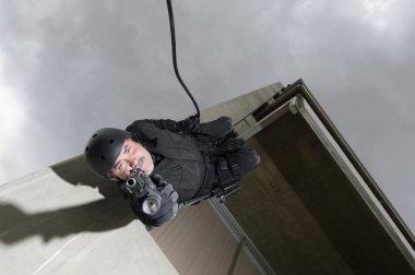 SWAT Team Officer Rappelling and Aiming Gun clipart