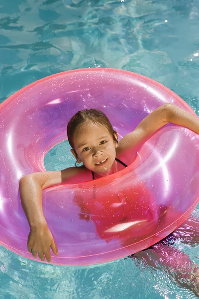 Ragazza dentro rosa galleggiante tubo in piscina — Foto Stock