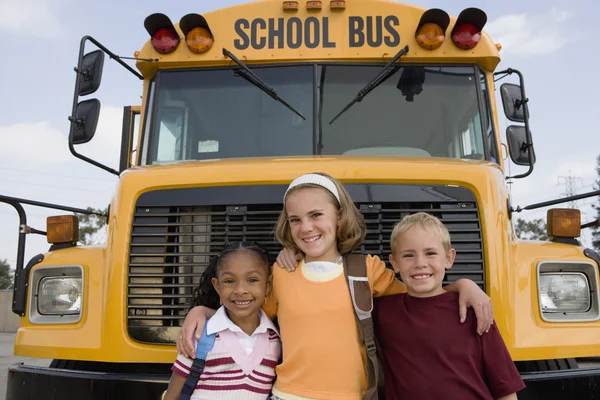 Студенты, стоящие перед школьным автобусом — стоковое фото