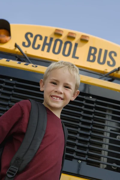 Pojken står framför skolbuss — Stockfoto