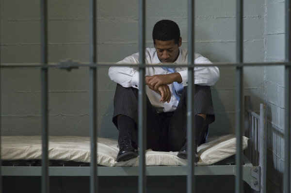Man Sitting On Bed In Prison Cell