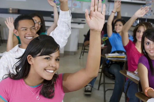 Schüler heben im Klassenzimmer die Hände — Stockfoto