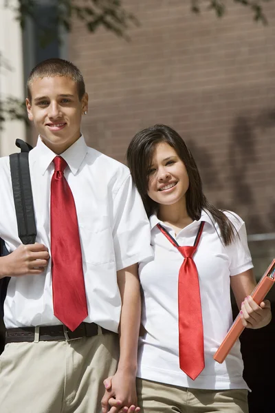 Casal do ensino médio em mãos de segurando uniforme — Fotografia de Stock