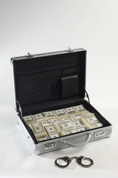 Чемодан и доллары с наручниками — стоковое фото