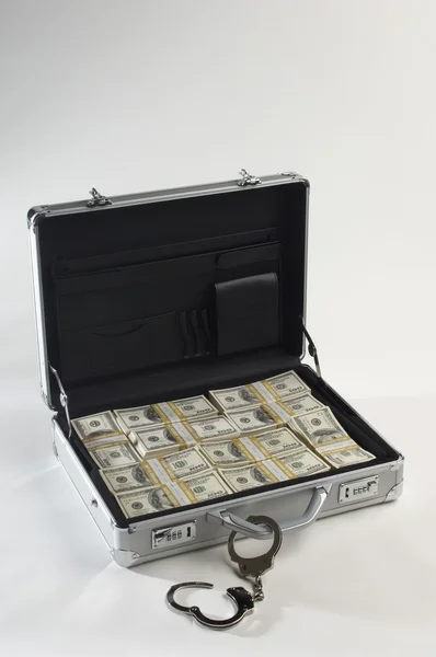 Чемодан и доллары с наручниками — стоковое фото