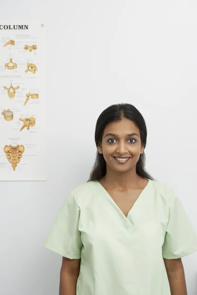 Lachende jonge vrouw met medische illustratie op de muur — Stockfoto