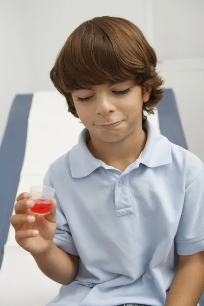 Niño sosteniendo la medicina en la medida líquida —  Fotos de Stock