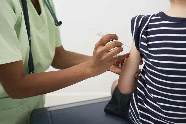 Médico inyectando jeringa en el brazo del niño — Foto de Stock