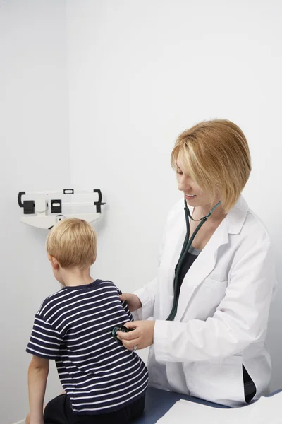 Doutor com estetoscópio examinando as costas do menino — Fotografia de Stock