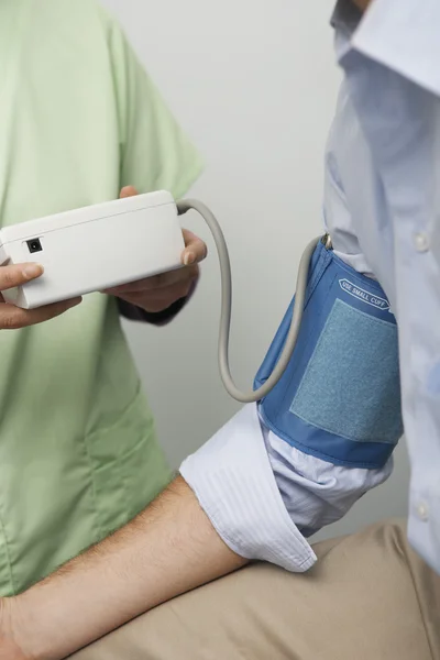 Médica verificando a pressão arterial do paciente — Fotografia de Stock