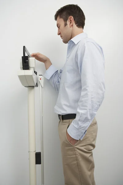 男を計量器に彼の重量を測定 — ストック写真