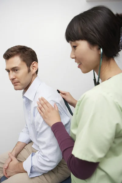 Médico examinando paciente usando estetoscópio — Fotografia de Stock