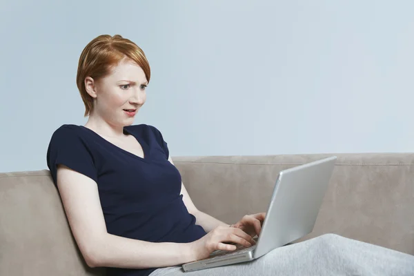 Junge Frau blickt überraschend auf Laptop — Stockfoto