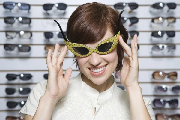 Mulher vestindo óculos de sol elegantes na loja — Fotografia de Stock