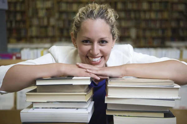 Mulher feliz apoiando-se na pilha de livros — Fotografia de Stock