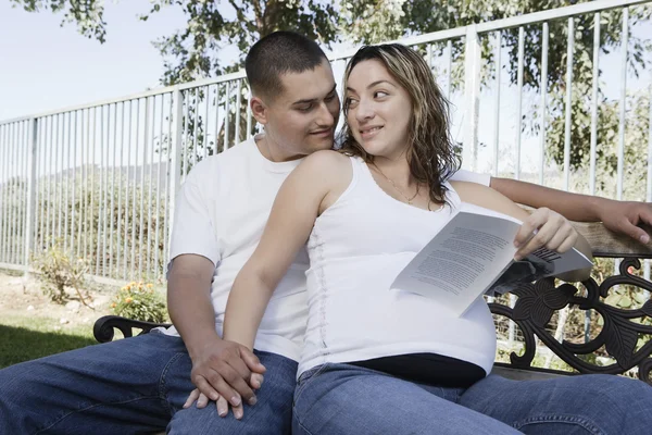 出産を控えたカップルのベンチに座っています。 — ストック写真