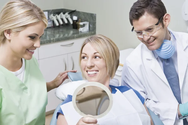 Dentista e paciente usando espelho — Fotografia de Stock