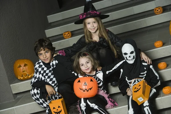 Děti v kostýmech halloween sedí na schodech — Stock fotografie