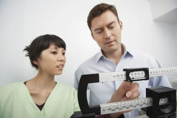 Nurse Adjusting Weighing Scale For Man — Stock Photo, Image