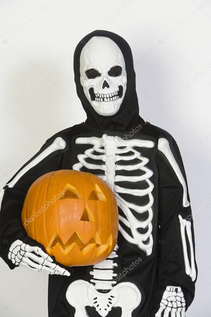 Child In Skeleton Costume Holding Jack-O-Lantern