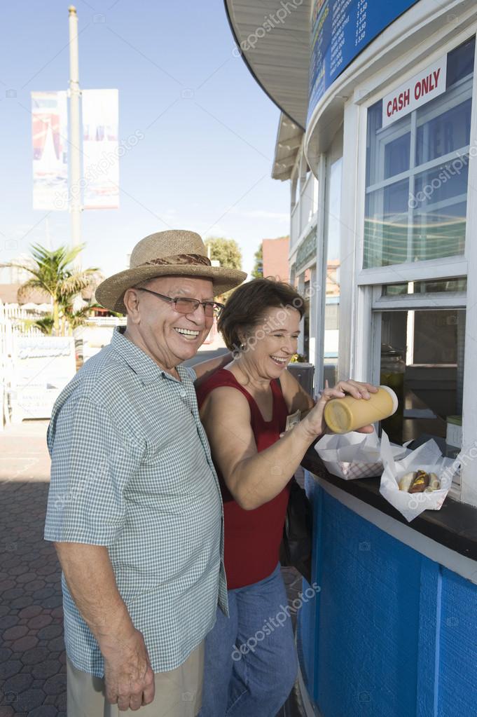 Senior Couple Buying Hot Dog At Food Stand