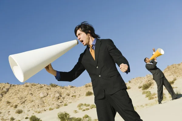 Uomini d'affari che urlano attraverso megafoni nel deserto — Foto Stock
