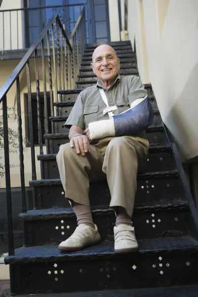 Hombre con el brazo roto sentado en las escaleras —  Fotos de Stock