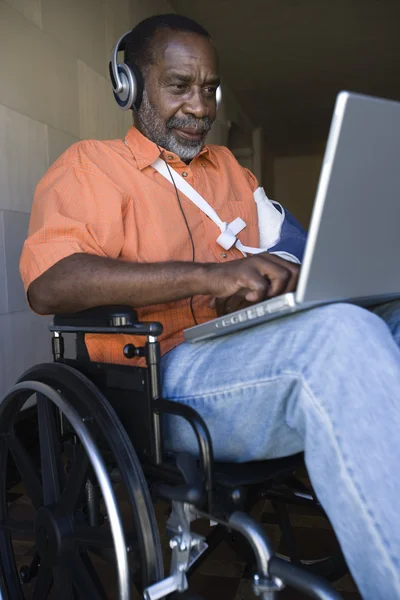 Hombre lesionado usando el ordenador portátil y escuchando música — Foto de Stock