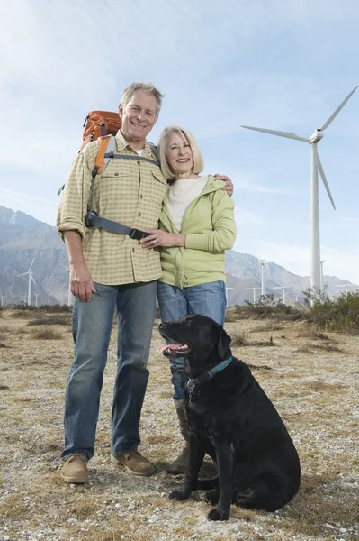 高级夫妇与风力农场附近的狗 — 图库照片