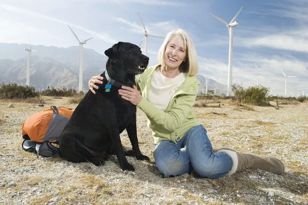 Senior mujer con perro cerca de parque eólico — Foto de Stock