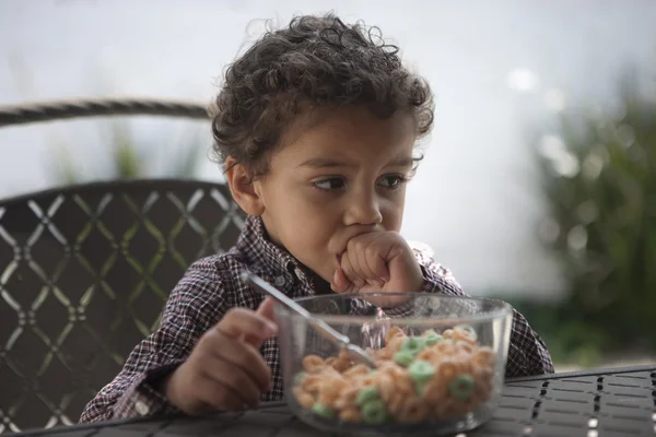 Ragazzino pensieroso che distoglie lo sguardo con ciotola di cereali sul tavolo — Foto Stock