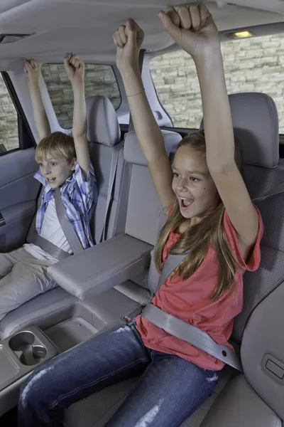 Cheerful children sitting at the back seat of car — Stok fotoğraf