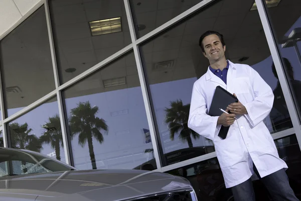 Glad bilhandlare som står framför bil showroom — Stockfoto