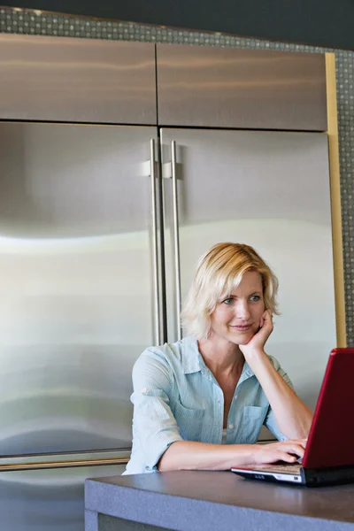 Senior woman with hand on chin using laptop — Stock Photo, Image