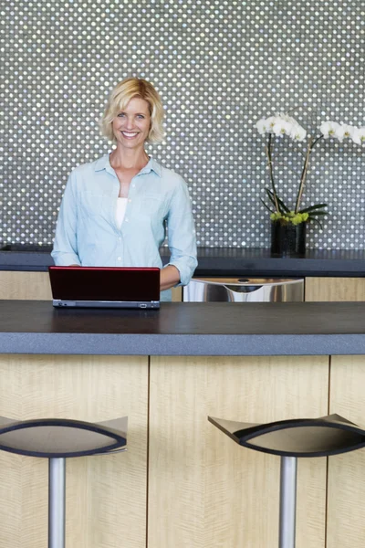 Retrato de mulher sorridente usando laptop na cozinha — Fotografia de Stock