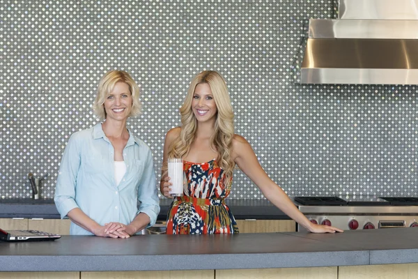 Portrait of smiling senior mother and daughter standing in kitchen — Stock Photo, Image