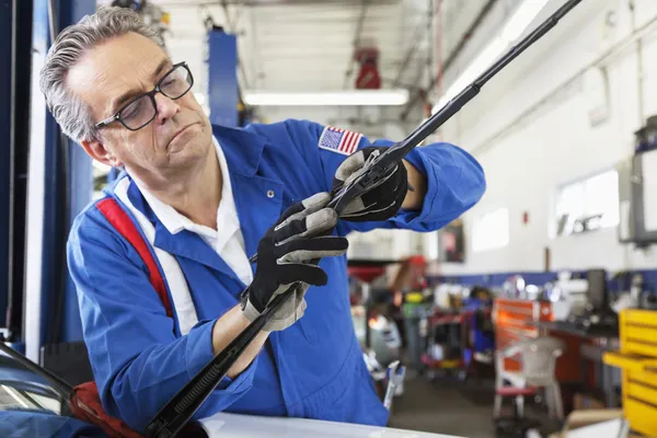 Mechanic working on windshield wipers of car — 图库照片