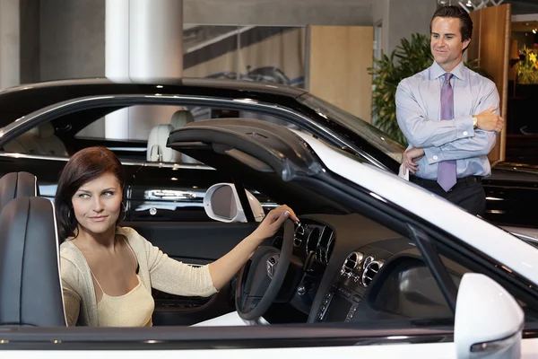 Femme ayant un essai routier tandis que le vendeur debout à côté de la voiture — Photo