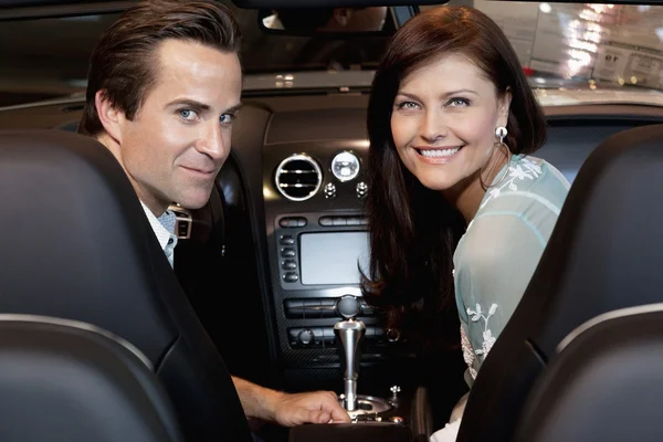 Pareja feliz sentada en su coche nuevo — Foto de Stock