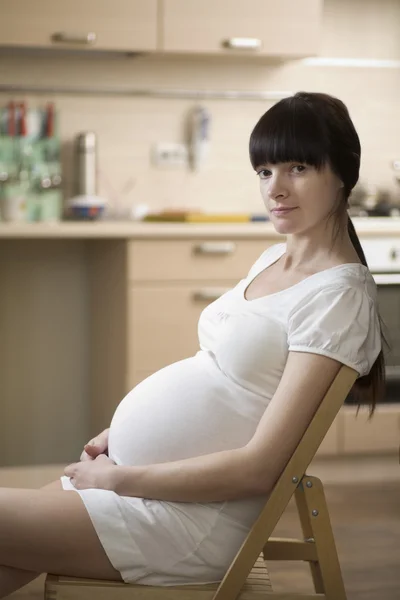 Retrato de una joven embarazada sentada en una silla — Foto de Stock