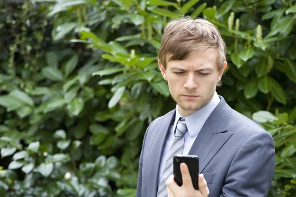 Junger Mann schaut aufs Handy — Stockfoto