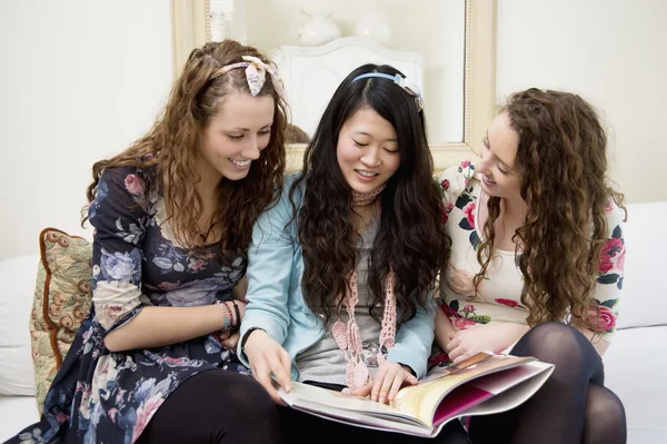 Jonge vrouwen kijken naar tijdschriften op een sofa — Stockfoto