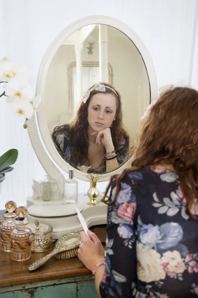 Pensive woman sitting at dressing table — Stock Photo, Image