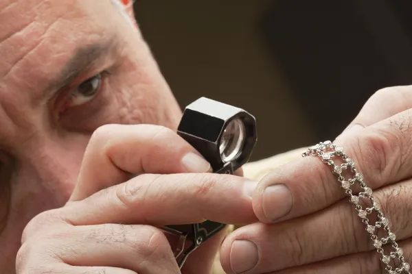 Close-up de homem olhando para jóias através de lupa — Fotografia de Stock