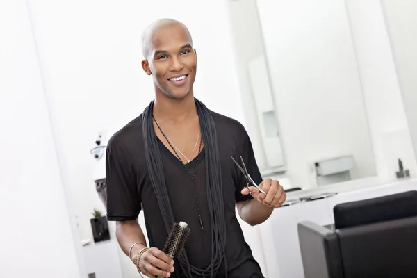 Coiffeur masculin souriant tenant ciseaux et brosse à cheveux — Photo