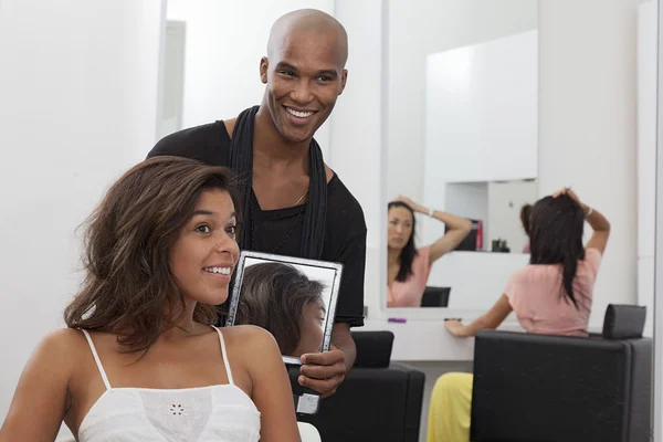 Fryzjer trzyma lustro za młodą kobietą — Zdjęcie stockowe