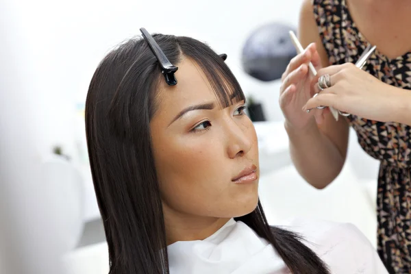 Hairstylist giving a haircut to Asian woman — Stock Photo, Image