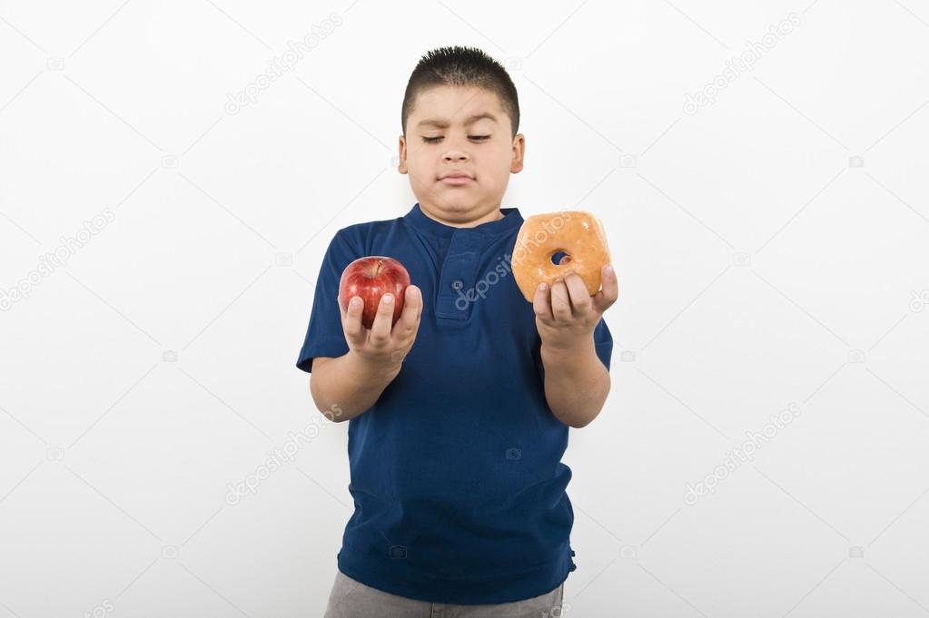 Boy Choosing Between Apple And Doughnut
