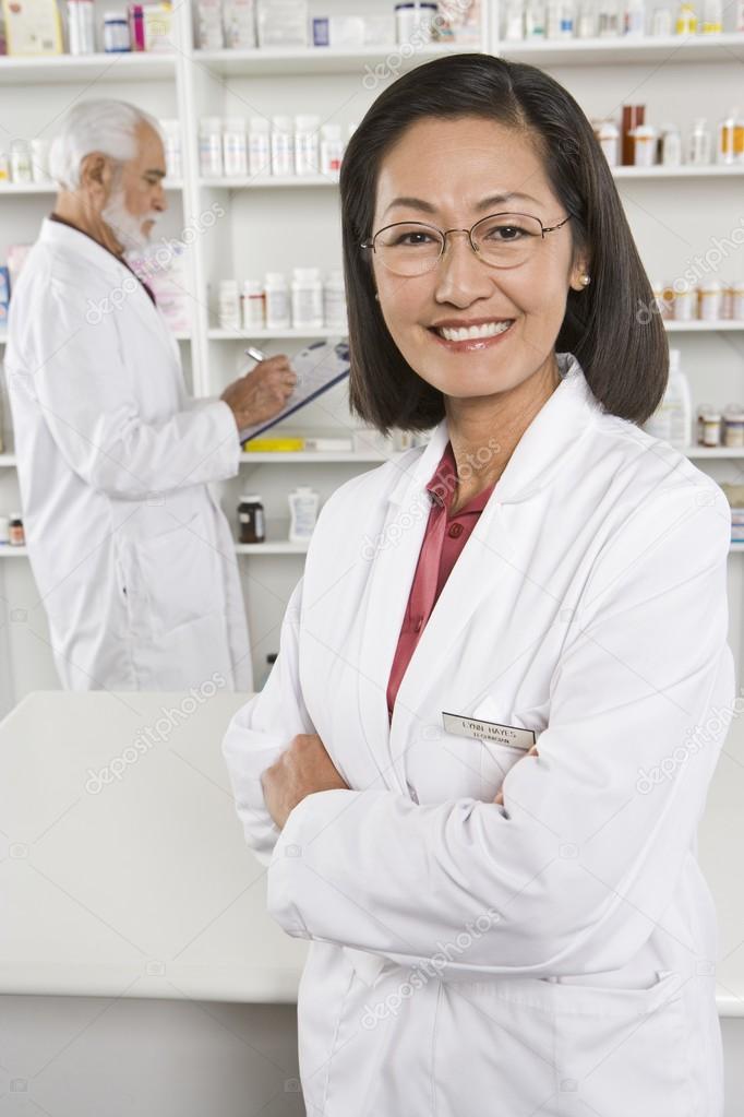 Confident Female Pharmacist Standing With Coworker