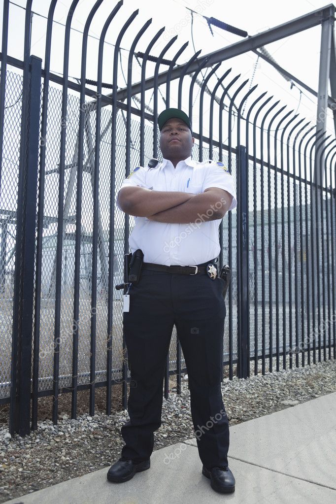 Security Guard Standing In Front Of The Prison Fence